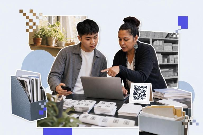 Two people discuss at a laptop with QR code cards on the table in an office setting.