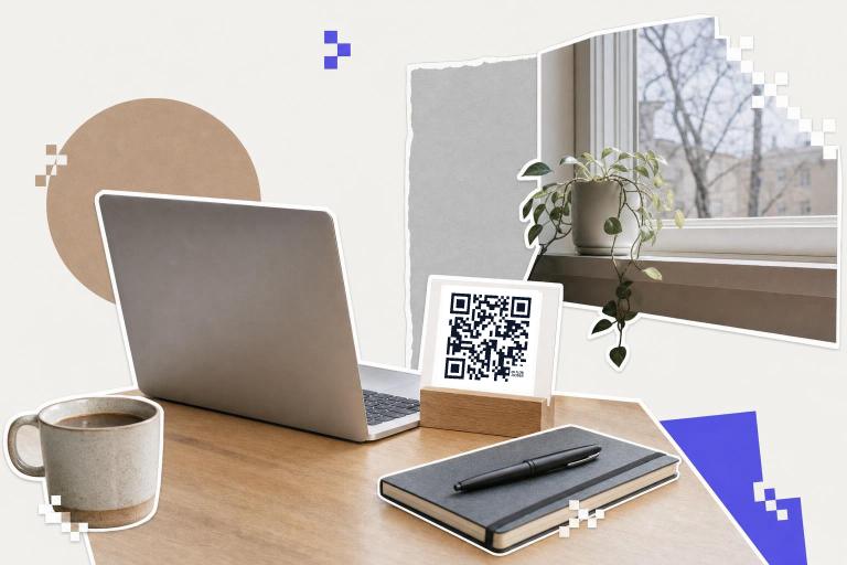 Laptop on desk with notebook, pen, coffee cup, and QR code card near window with plant.