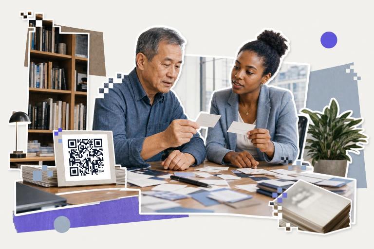 Two people discussing business cards at a table with a QR code display nearby in an office setting., how to create a qr 