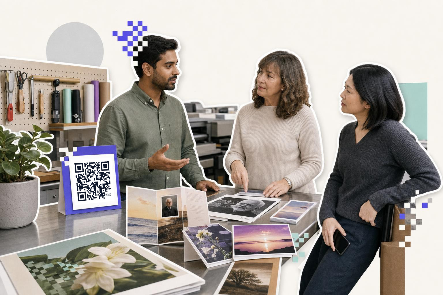 Three people discuss printed photos on a table with a QR code card nearby in a workshop setting.